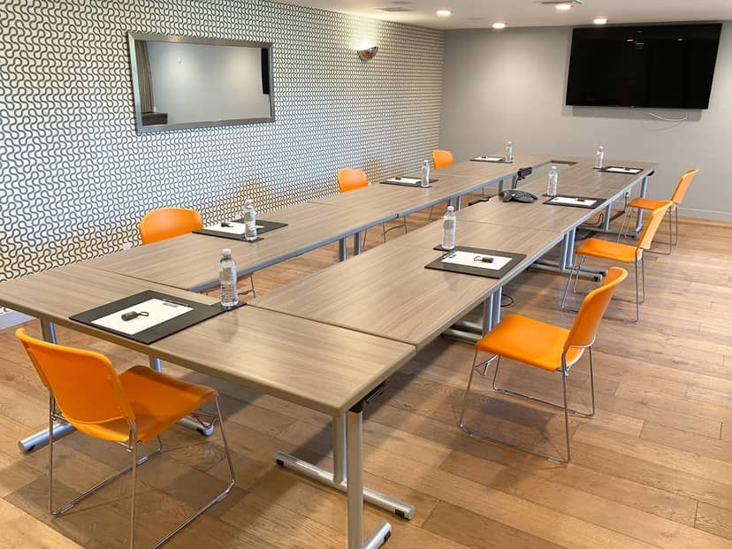 Meeting room with U-shaped tables, orange chairs for professional gatherings and workshops.