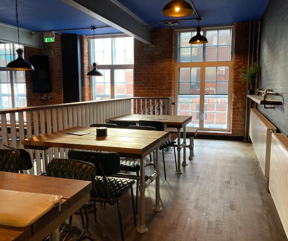 Versatile industrial event space with wooden tables and natural light for meetings and gatherings.