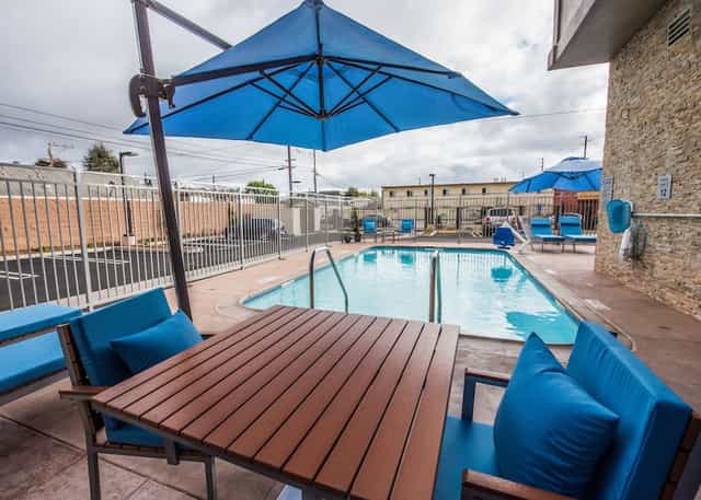 Outdoor pool at Hollywood Suites Inn with blue umbrellas, ideal for events and relaxation.