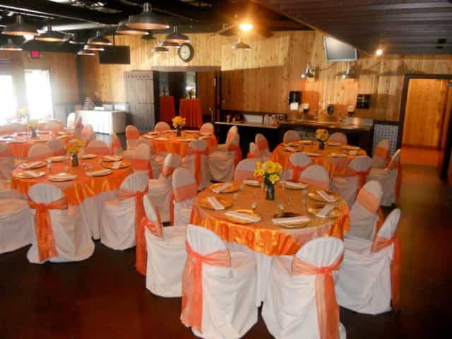 Main Room at Phil's BBQ Event Center with orange linens, ideal for weddings and corporate events.