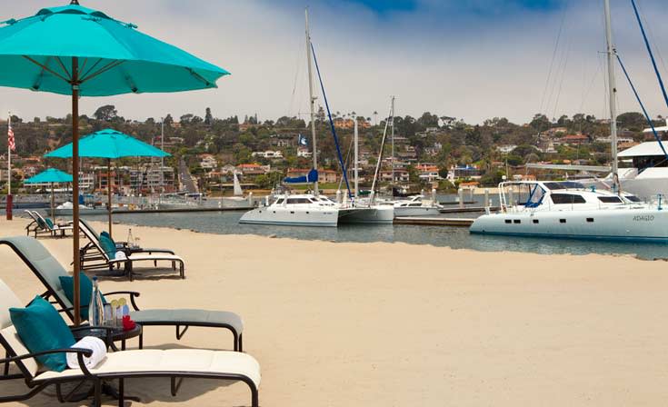 Private beach at Kona Kai Resort, ideal for outdoor events with vibrant umbrellas and sailboats.