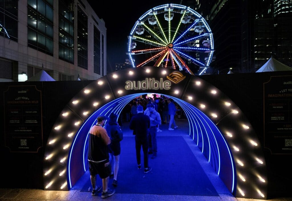 Vibrant event entrance with illuminated archway and ferris wheel for branded activations.