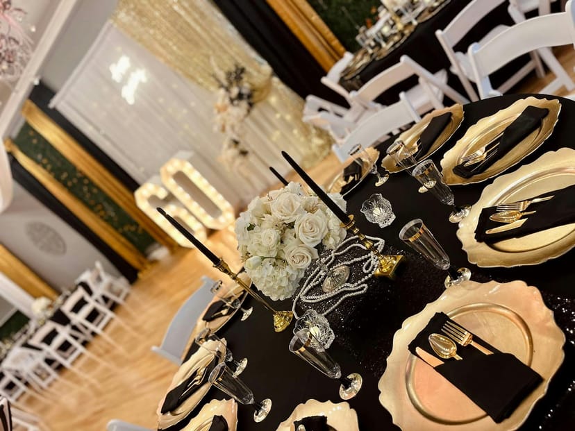 Elegant black and gold table setting with white roses for weddings and upscale events.