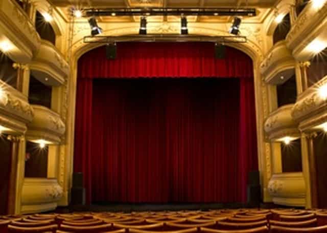 Elegant theater stage with red curtain in 268-seat venue for events and performances.