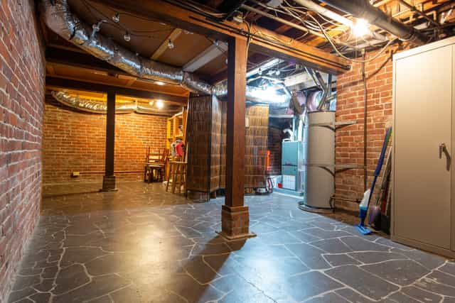 Spacious unfinished basement with exposed brick for unique event spaces or workshops.