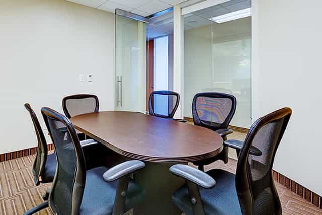 Modern conference room with oval table and glass walls for collaborative meetings.