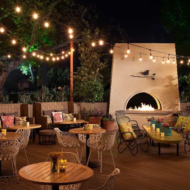 Cozy outdoor event space with string lights and fireplace for gatherings at The Oak and Vine.