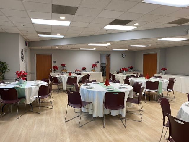 Meeting room with round tables and white tablecloths for community events and gatherings.