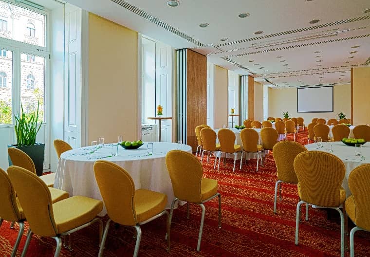 Meeting room with round tables and yellow chairs at Courtyard by Marriott for events.
