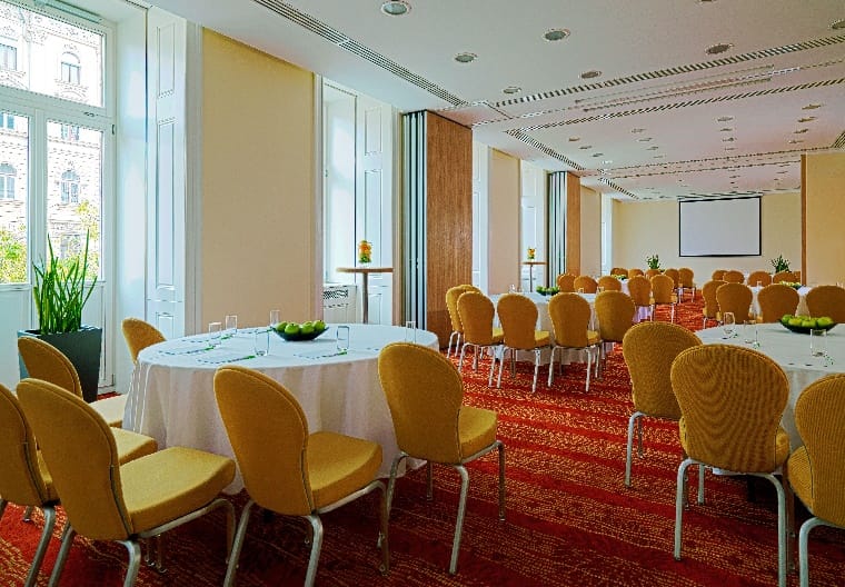 Meeting room with round tables and yellow chairs at Courtyard by Marriott for events.