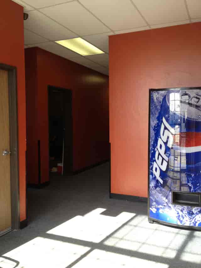 Monthly Studios corridor with vibrant orange wall and Pepsi vending machine for casual breaks.