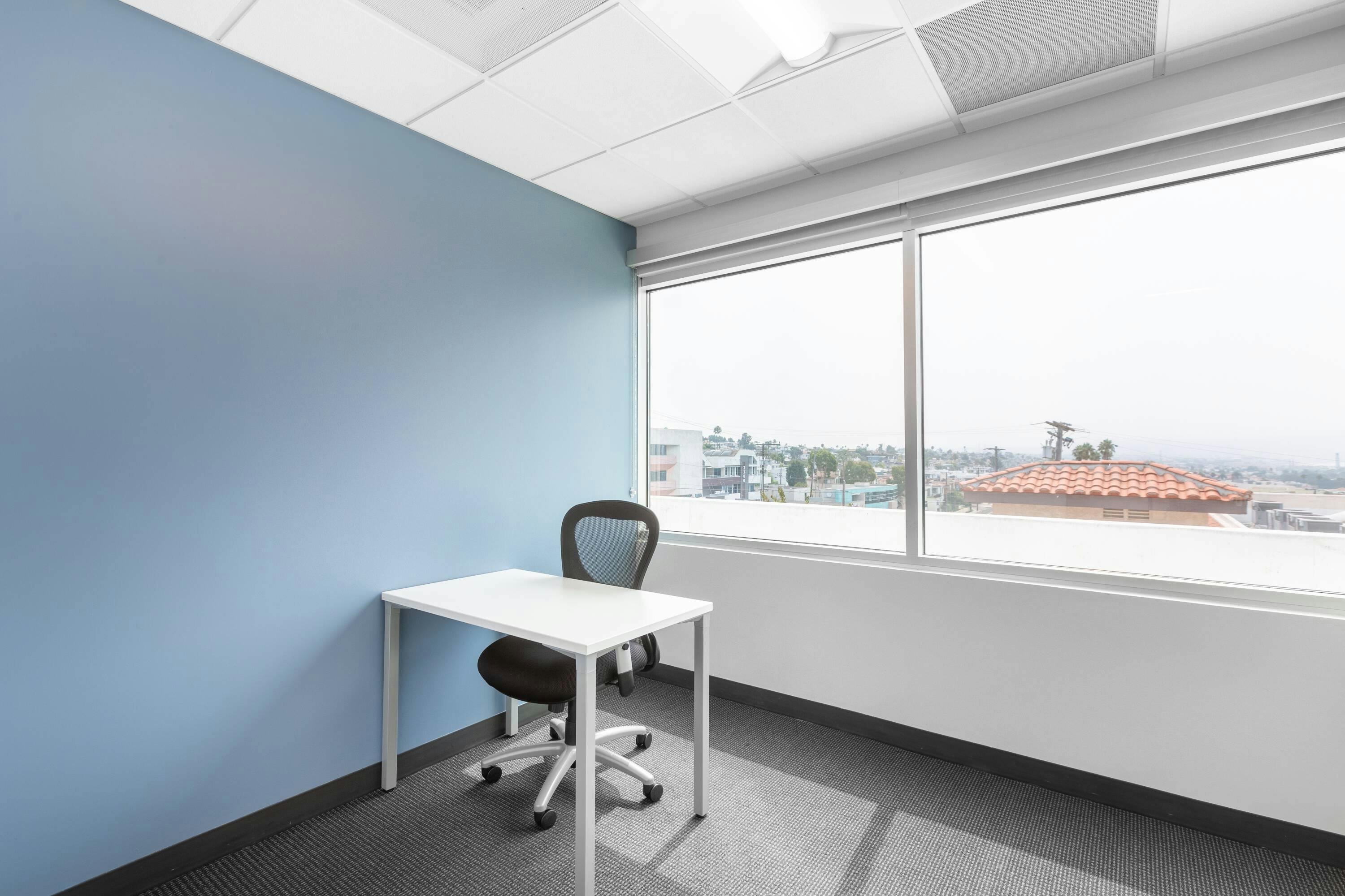 Minimalist office meeting space with desk, chair, and natural light for productive sessions.