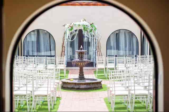 Elegant outdoor wedding setup at Cantina Courtyard with white chairs and floral arch.