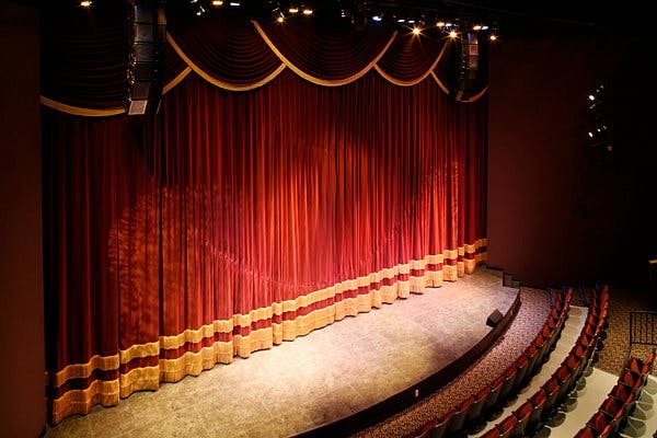 Aurora Theater stage with red curtains, ideal for performances and conferences.