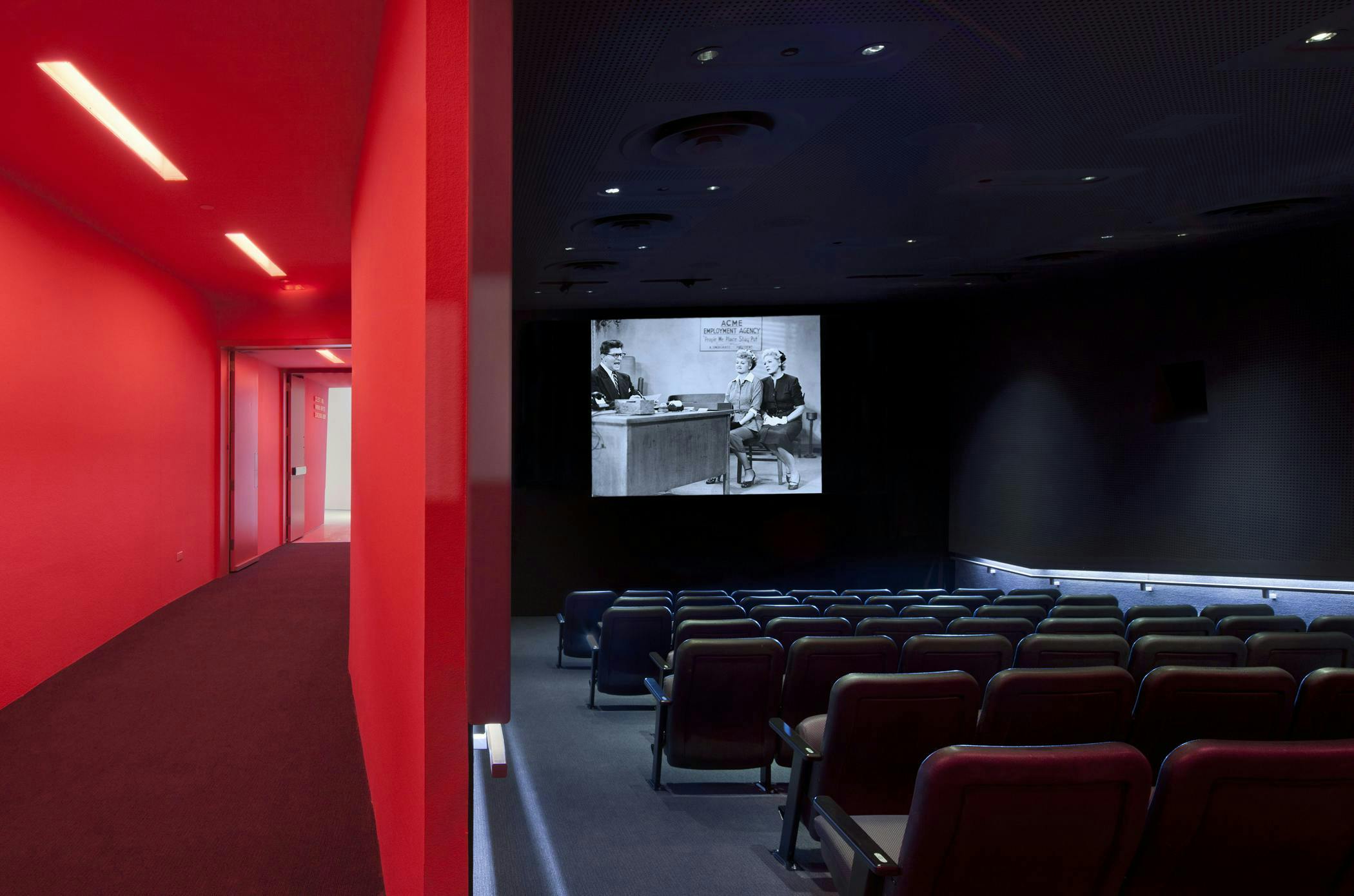 Modern screening room with tiered seating and red accents, ideal for presentations and film events.