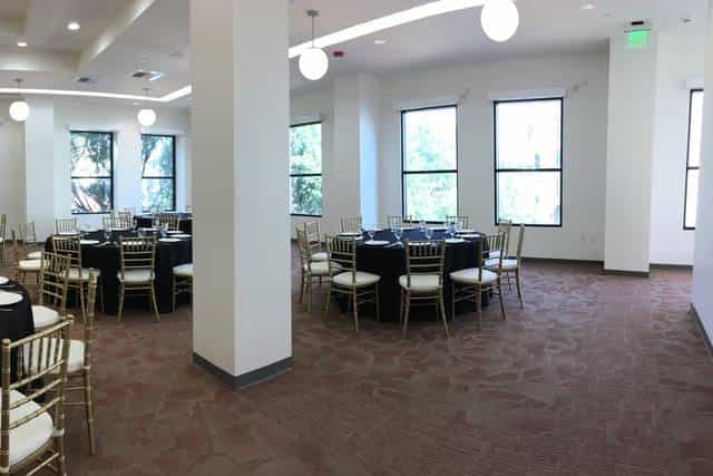 Elegant event space in Pasadena Hotel with round tables, ideal for gatherings and networking.