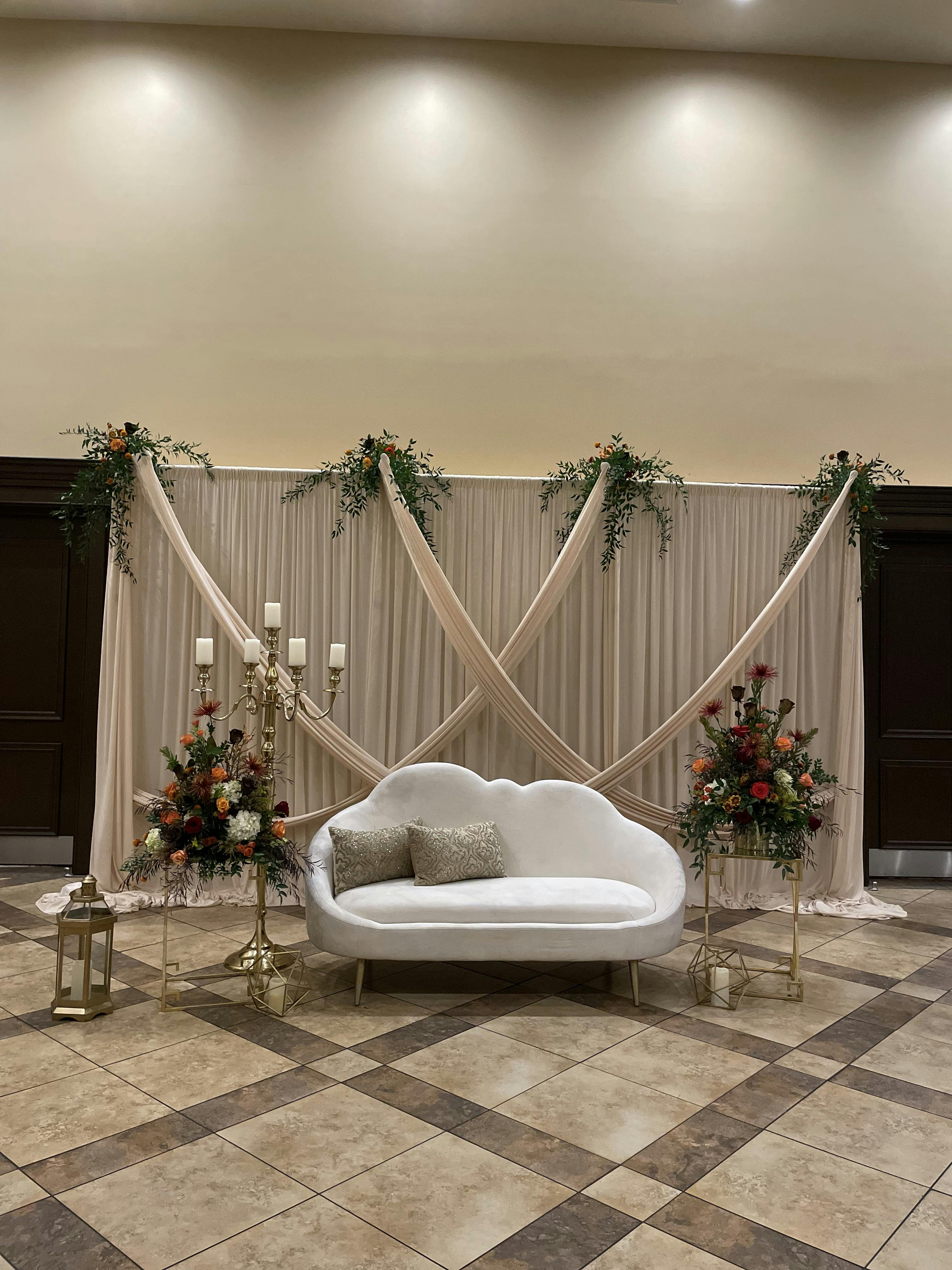 Elegant event backdrop with drapery and floral arrangements at Historic Hall, Artesia.