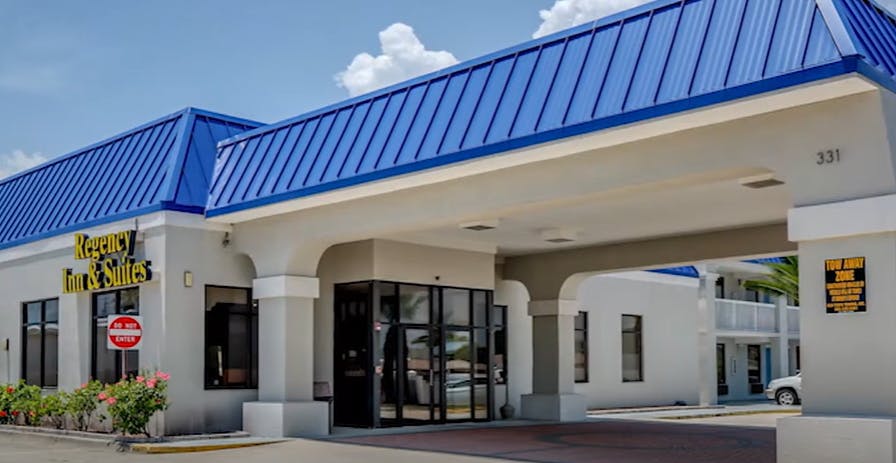 Modern Regency Inn & Suites entrance with blue roof, ideal for events and meetings.