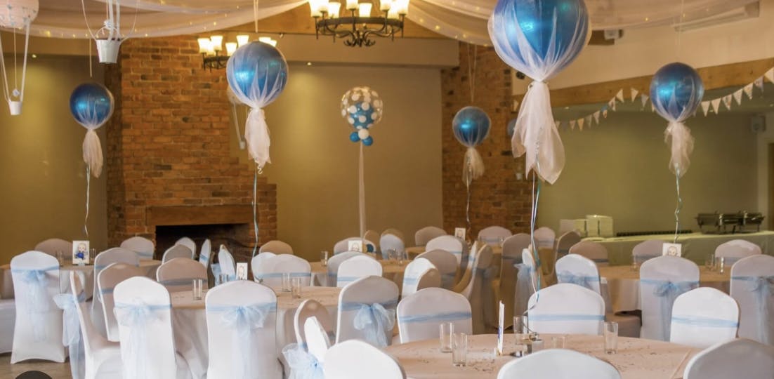 Bridal party in elegant event space with blue balloon centerpieces for weddings.