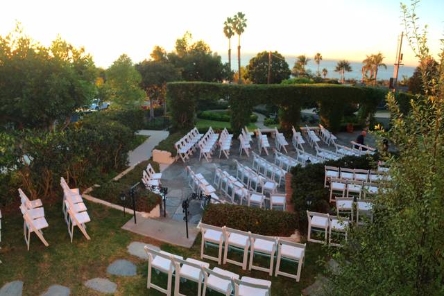 Outdoor event space with white chairs, palm trees, ideal for weddings and corporate events.