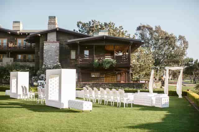 Elegant outdoor wedding setup with white seating and lush green lawn.