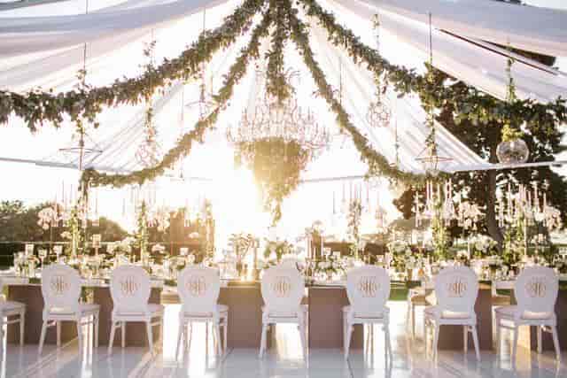 Elegant outdoor wedding venue with draped greenery and floral arrangements.