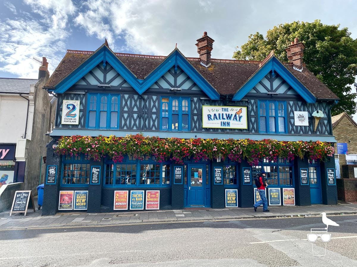Charming Railway Inn pub with vibrant flowers, perfect for casual gatherings and events.