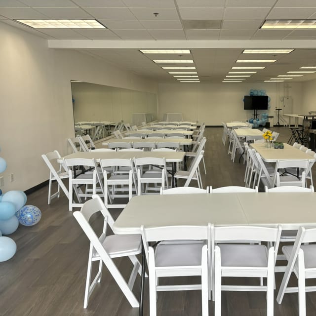 Versatile event space with white tables, perfect for meetings and celebrations.