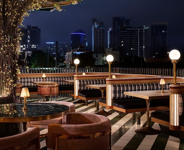 Rooftop patio at Born and Raised with city skyline, perfect for evening events and gatherings.