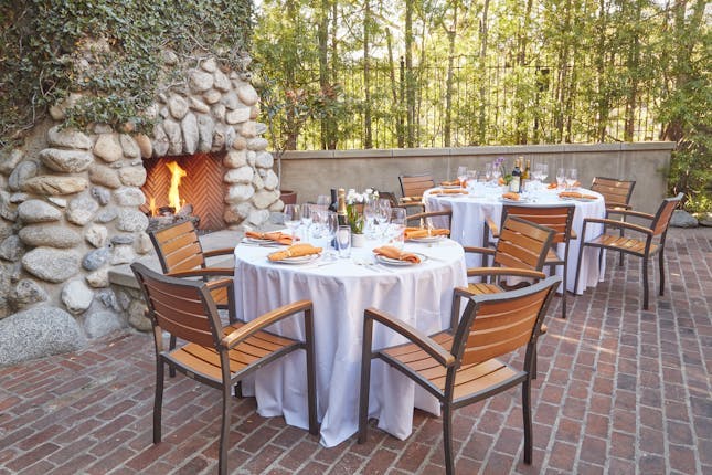 Outdoor dining setup at Fireside Terrace, featuring elegant tables and a cozy fireplace.