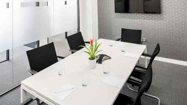 Modern conference room with sleek table, ideal for small meetings and presentations.