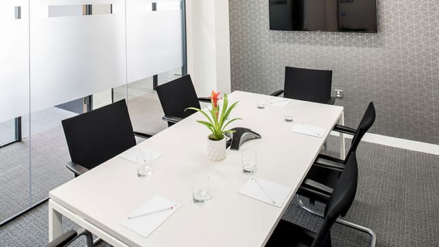 Modern conference room with sleek table, ideal for small meetings and presentations.