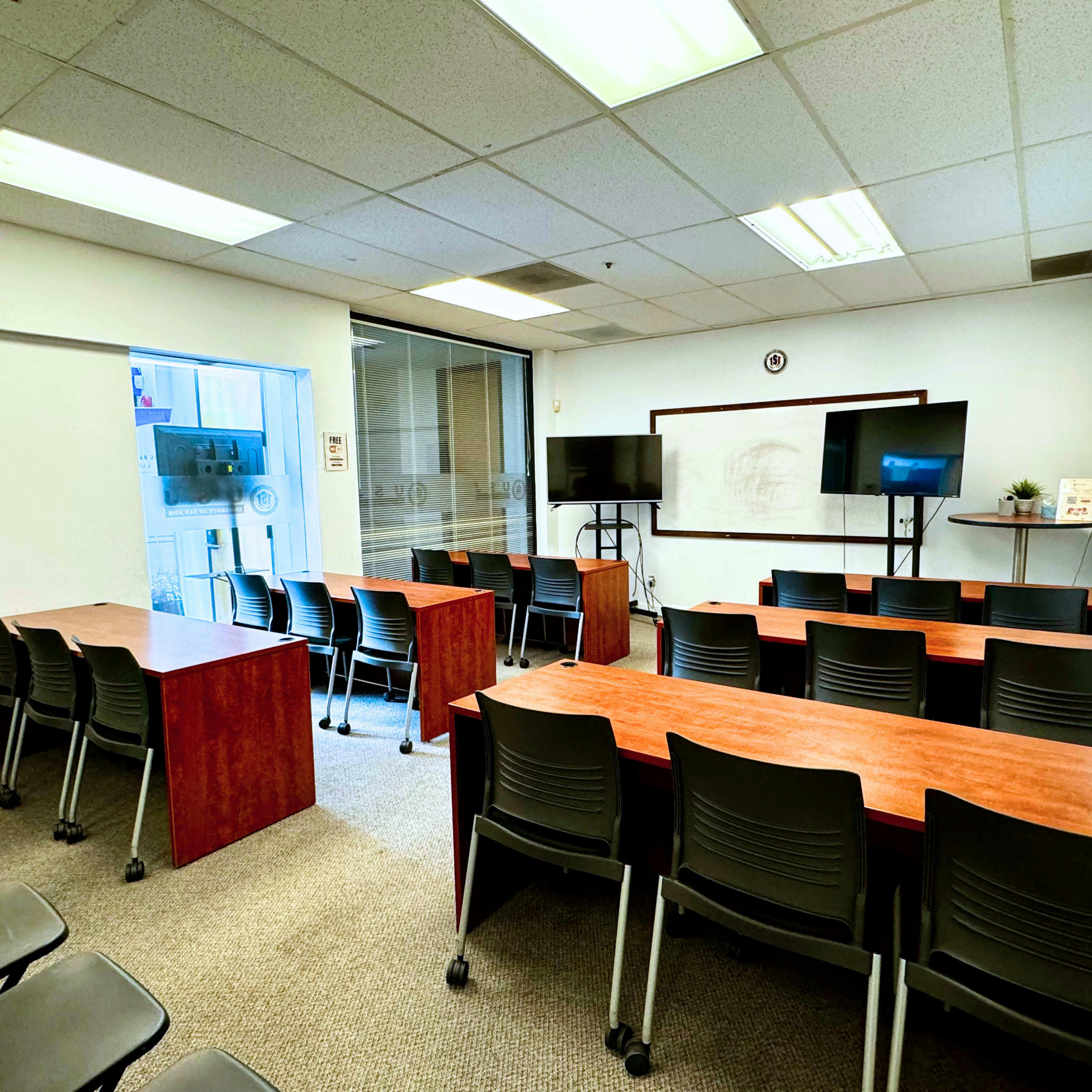 Versatile teaching room with modular tables and dual screens for workshops and training.