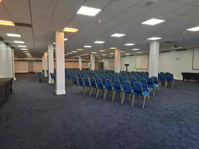 Spacious Saffron Suite conference venue with blue chairs, ideal for seminars and workshops.