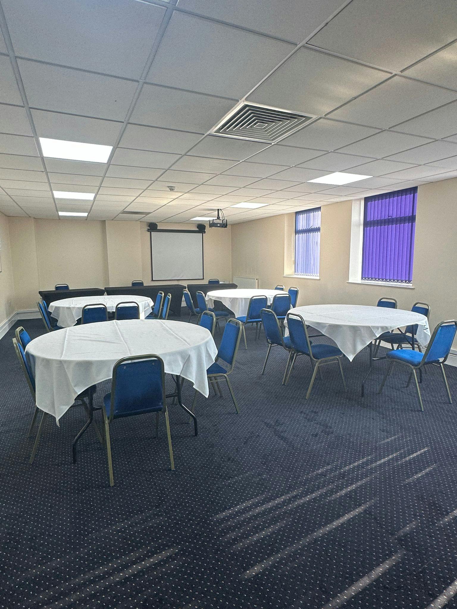 Versatile meeting room with round tables, ideal for workshops and conferences.