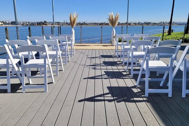 Tower Beach Club wedding venue with white chairs and waterfront backdrop, perfect for events.