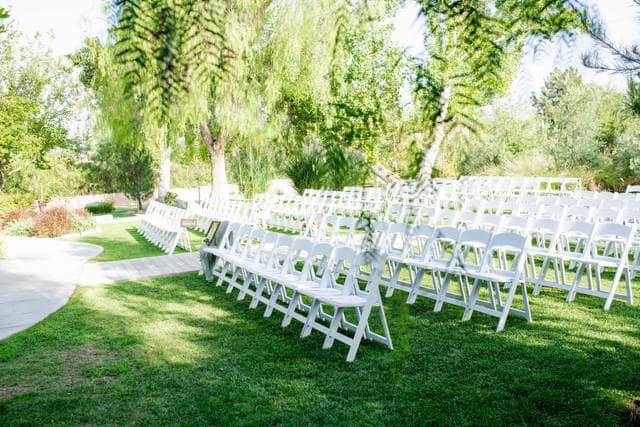Outdoor wedding seating area with white chairs on lush grass at Harmony Estate.