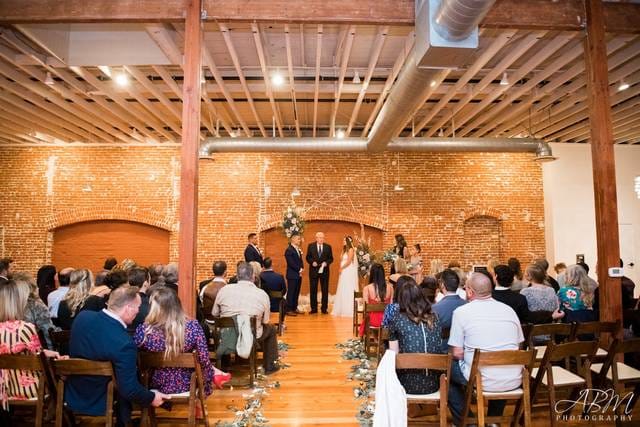 Rustic wedding ceremony in Banquet Hall with floral altar and warm lighting.