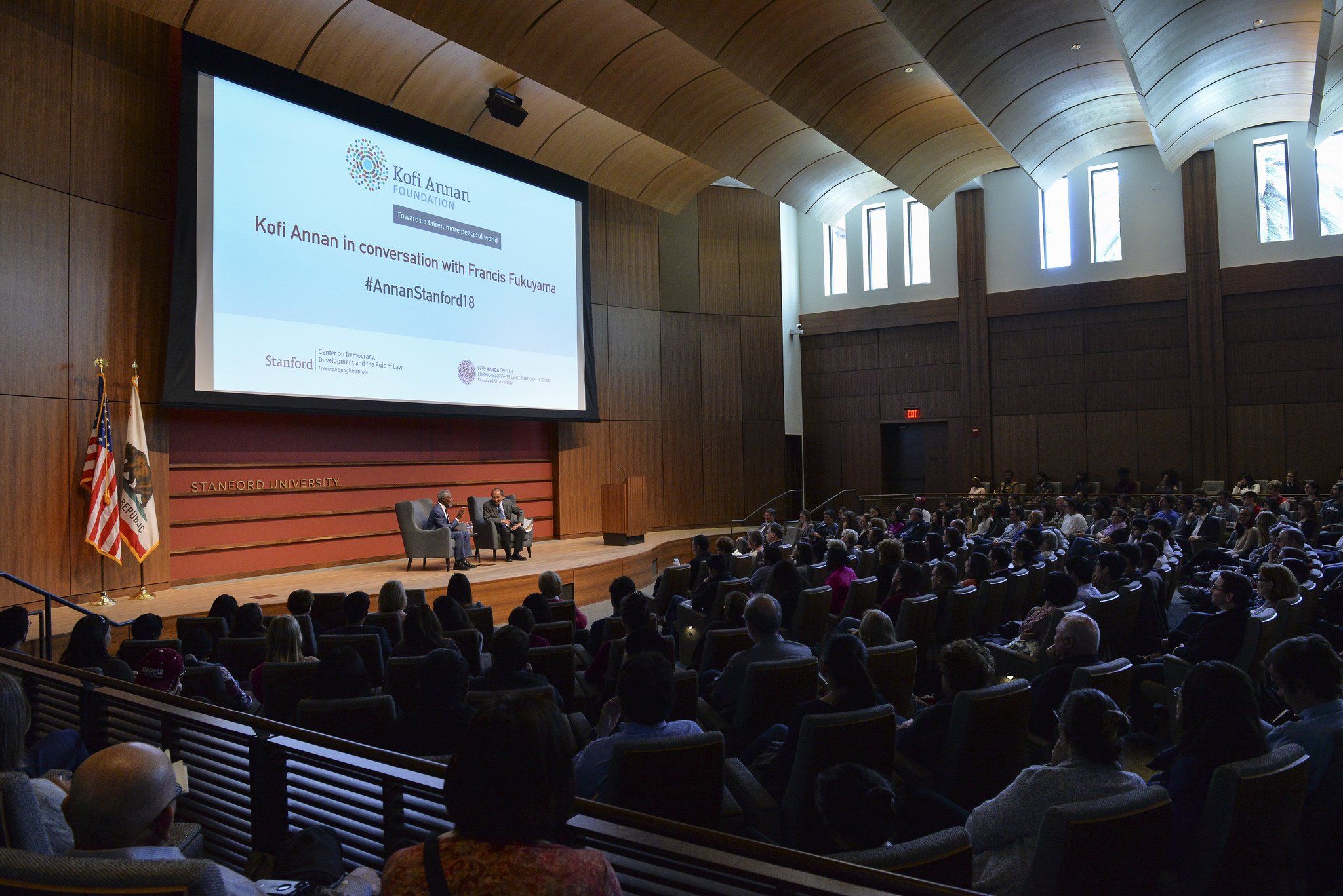 Encina Hall panel discussion with tiered seating and large screen for audience engagement.