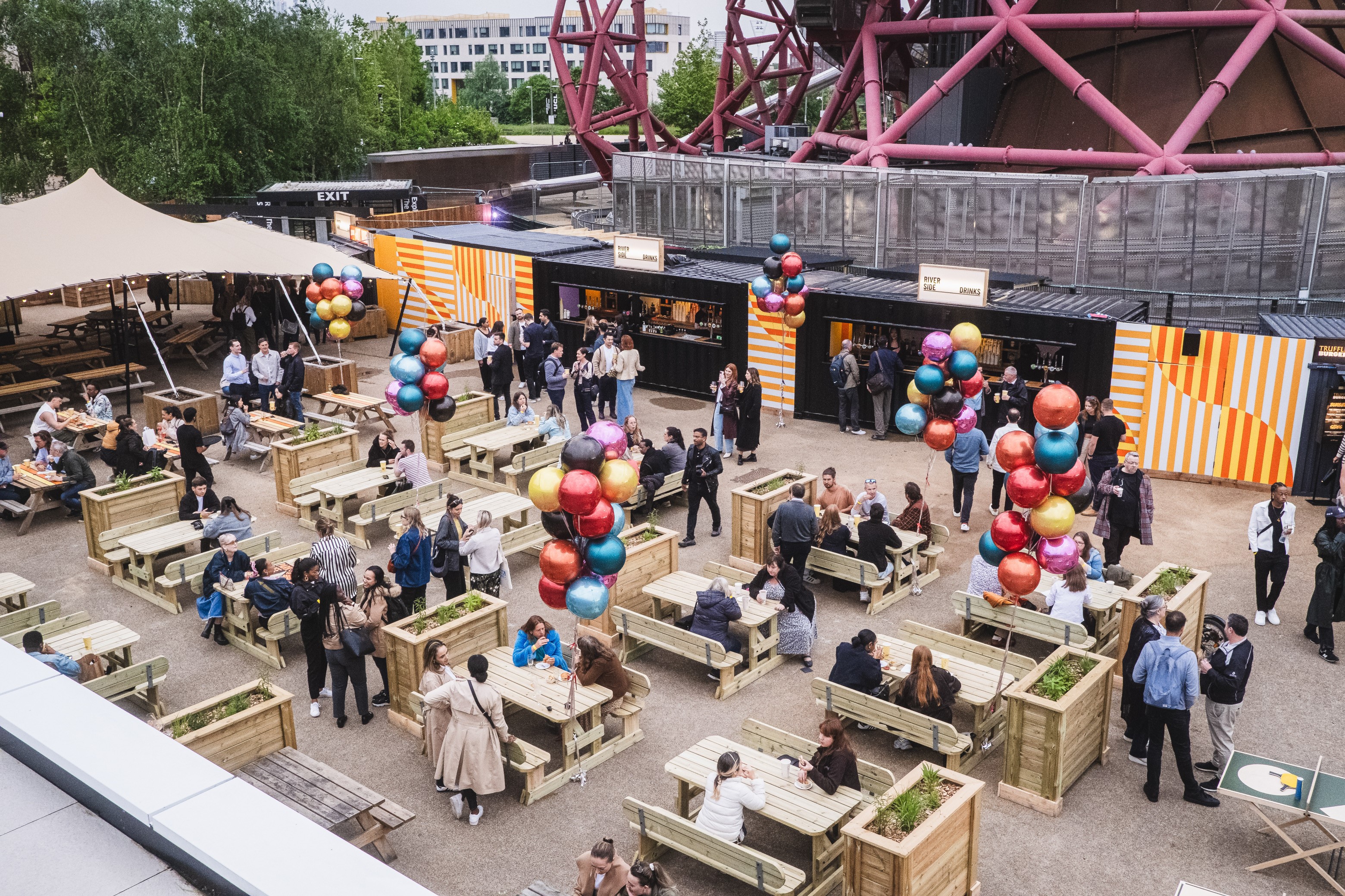 Vibrant outdoor event space with communal seating and colorful balloons for networking.