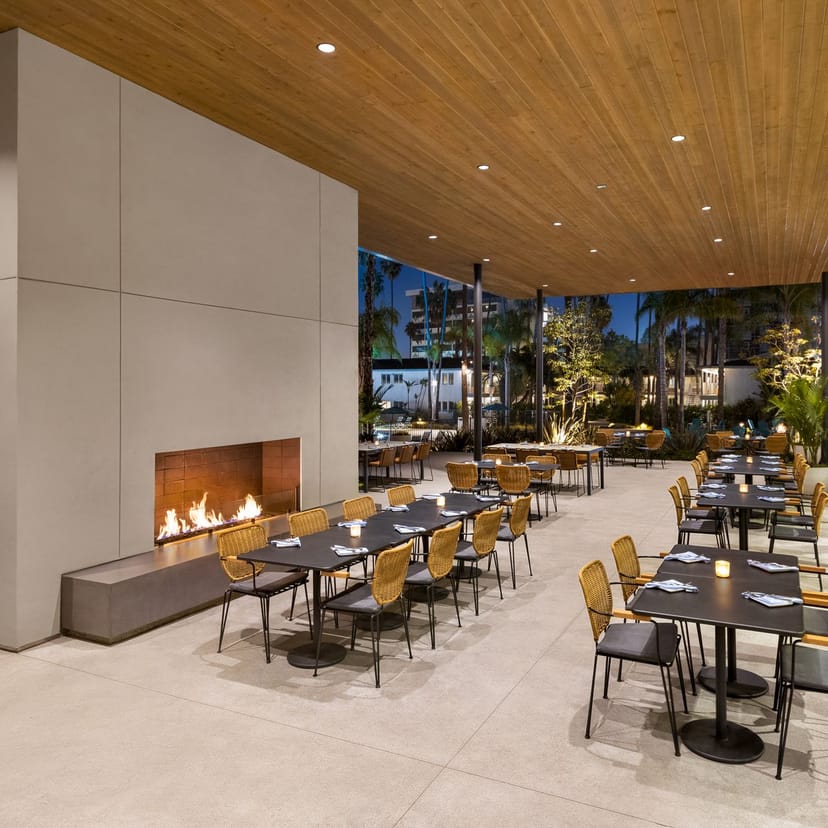 Modern outdoor dining at ARLO San Diego with sleek tables and inviting fireplace ambiance.
