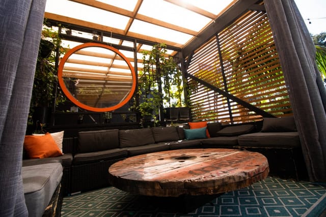 Outdoor meeting space at 1835 Studios with unique wooden table and lush greenery.