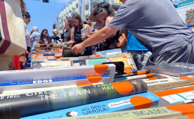 North Park Playwright Festival: vibrant outdoor book display promoting literacy and community.