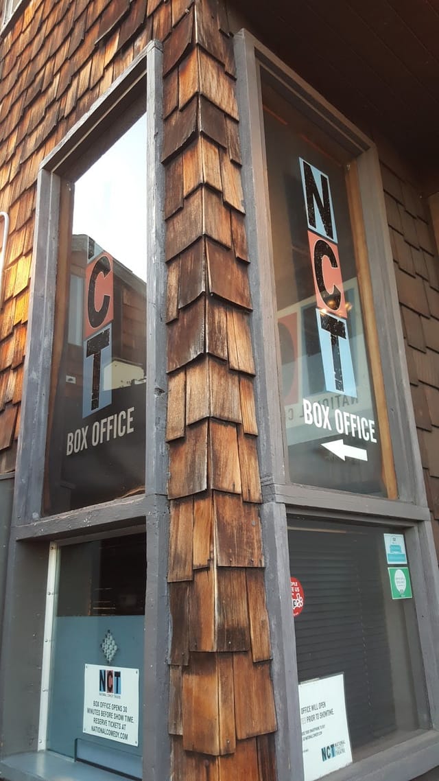 "National Comedy Theatre box office with rustic wooden exterior for smooth event access."