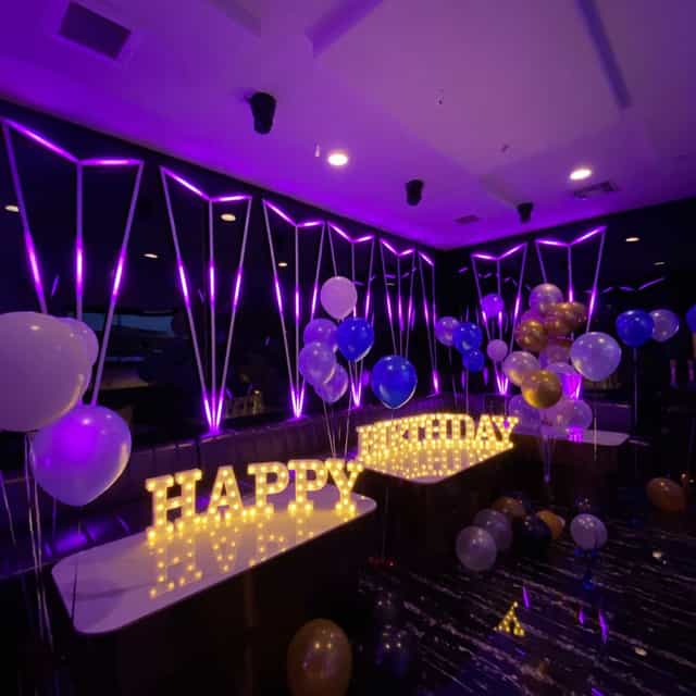 Vibrant birthday karaoke setup with "HAPPY BIRTHDAY" sign and colorful balloons.