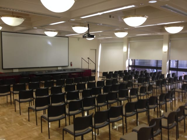 Spacious De Anza College conference room set for a seminar with black chairs and projection screen.