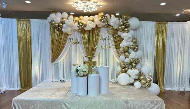 Elegant gold and white event backdrop with balloon arch at Moonlite Center, ideal for weddings.