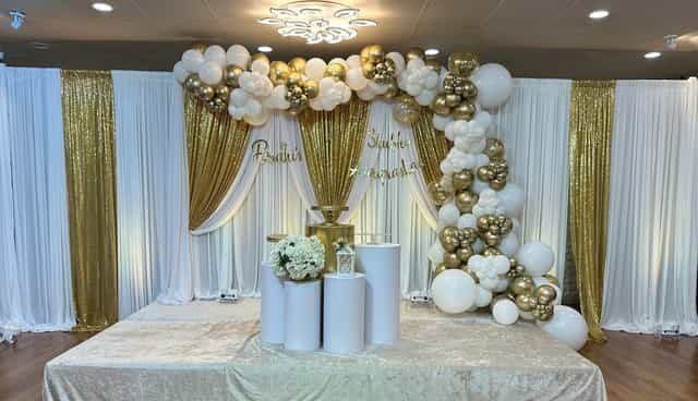 Elegant gold and white event backdrop with balloon arch at Moonlite Center, ideal for weddings.