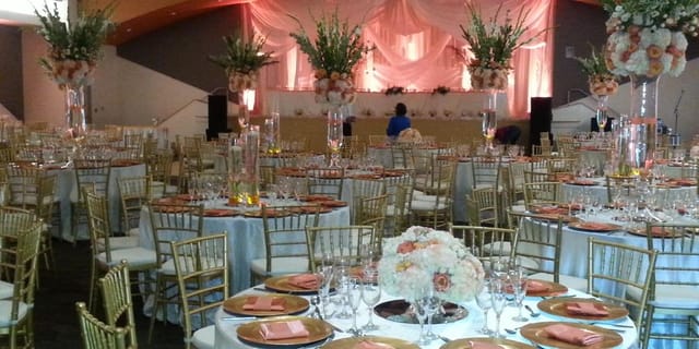 Elegant Indian wedding venue with round tables, white linens, and gold accents.