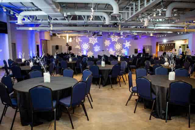 Elegant event space with black linens and snowflake projections for formal gatherings.